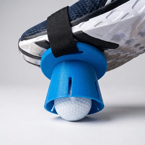 Ball Foot golf ball retriever strapped on a golf shoe holding a golf ball